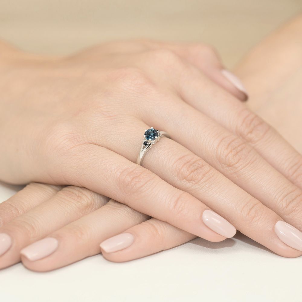 Pierścionek z topazem London Blue 0,50 ct i czarnymi brylantami, białe złoto 585, zdjęcie na dłoni