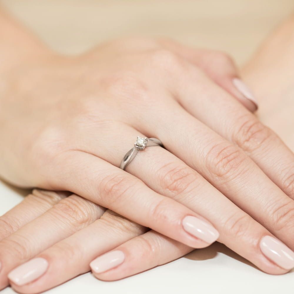 Pierścionek zaręczynowy z brylantem 0,12 ct, białe złoto 585, zdjęcie na dłoni